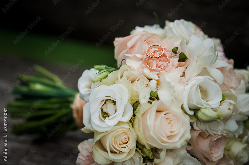Gold wedding rings and colorfull bouquet of flowers