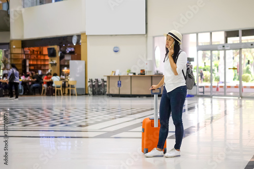 Asian women are standing on their mobile phones to check in or search for travel information at the airport.