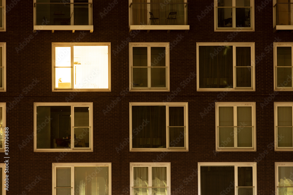 Single lit window in a modern apartment block Single lit window in a modern apartment block