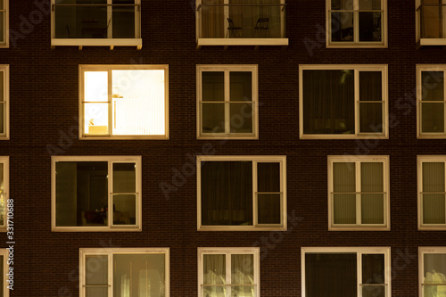 Single lit window in a modern apartment block