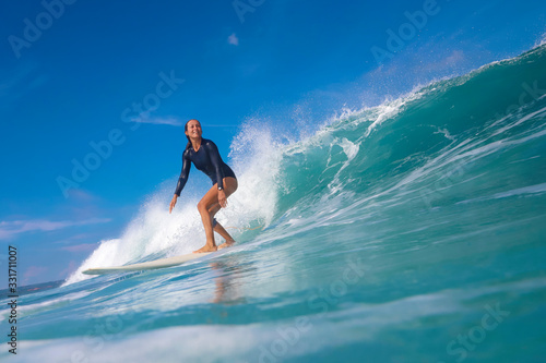 Female surfer on a blue wave © trubavink