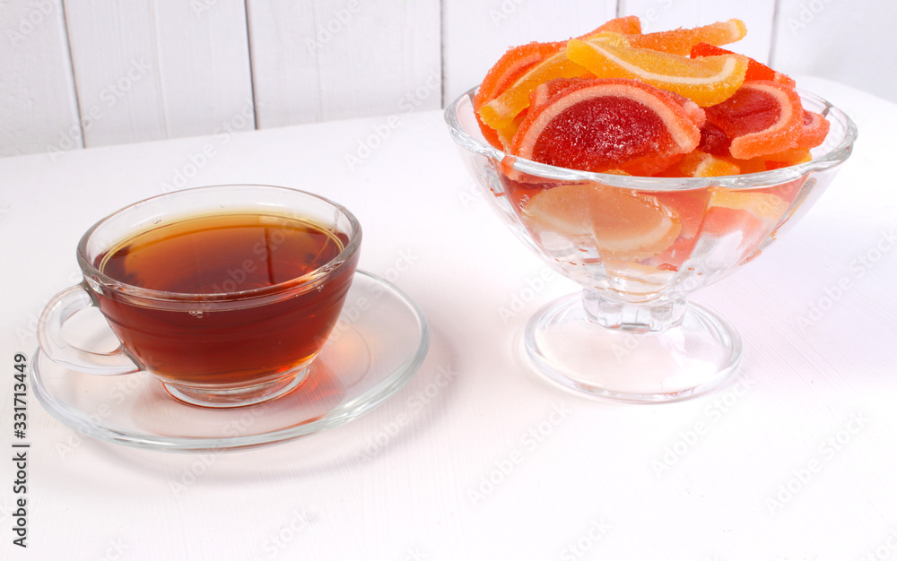 a Cup of tea and citrus marmalade in a candy bowl on a white background a Cup of tea and citrus marmalade in a candy bowl on a white background