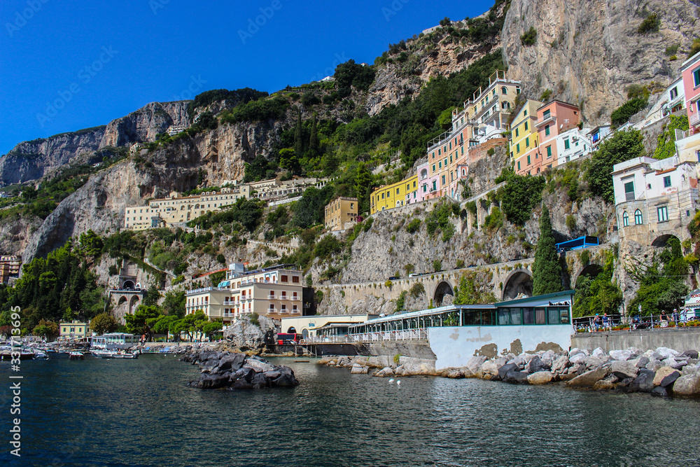 View of the town of Amalfi from the jetty with the sea and the colorful houses on the slopes of the Amalfi coast in the province of Salerno, Campania, Italy.