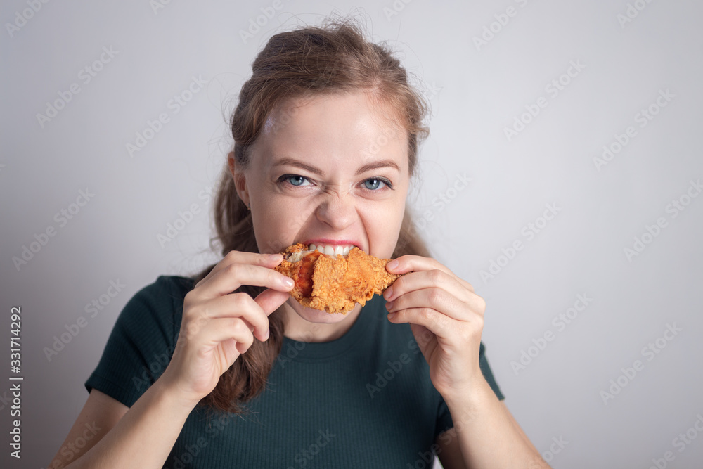 Smiling young Caucasian woman girl holding eating fried chicken drumstick Smiling young Caucasian woman girl holding eating fried chicken drumstick