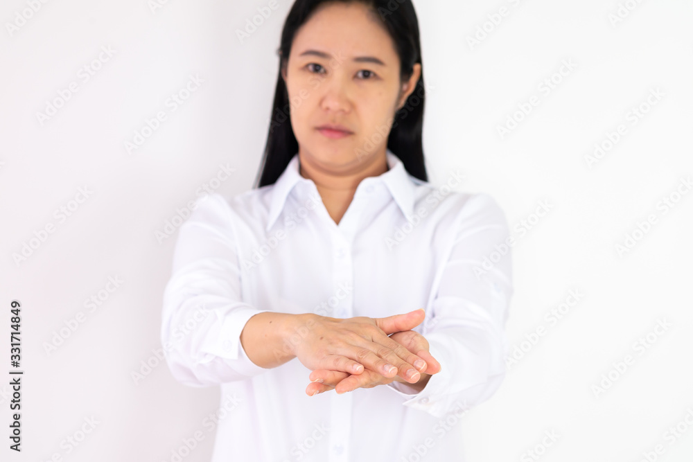 An Asian woman wearing a white shirt is washing her hands with alcohol gel to protect against corona virus or covid 19 on a white background. An Asian woman wearing a white shirt is washing her hands with alcohol gel to protect against corona virus or covid 19 on a white background.