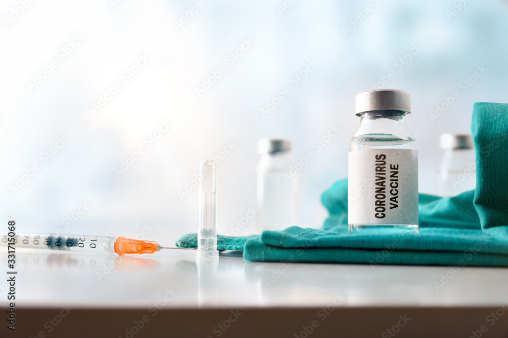 Vial and syringe with coronavirus dose on table hospital front Vial and syringe with coronavirus dose on table hospital front