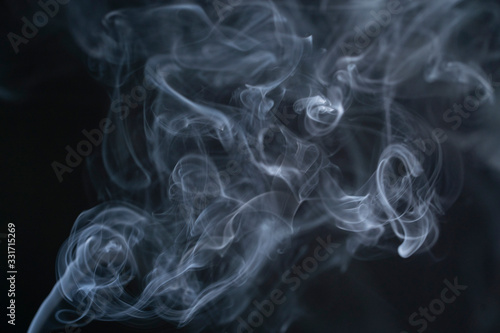 Blue isolated smoke on a black background. The mist is moving up, color of the indigo. The fog dissolves beautifully into different shapes in the air