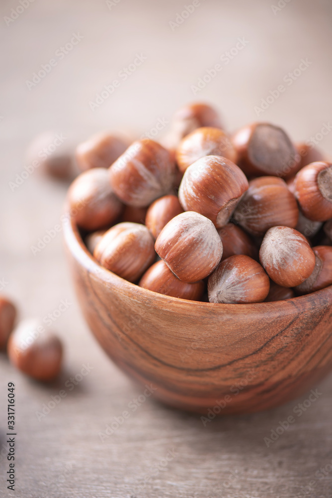 Hazelnuts in wooden bowl on wood textured background. Copy space. Superfood, vegan, vegetarian food concept. Macro of hazelnut, selective focus. Healthy snack. Hazelnuts in wooden bowl on wood textured background. Copy space. Superfood, vegan, vegetarian food concept. Macro of hazelnut, selective focus. Healthy snack.