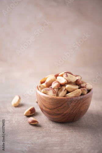 Brazil nuts in wooden bowl on wood textured background. Copy space. Superfood, vegan, vegetarian food concept. Macro of brazil nut texture, selective focus. Healthy snack.