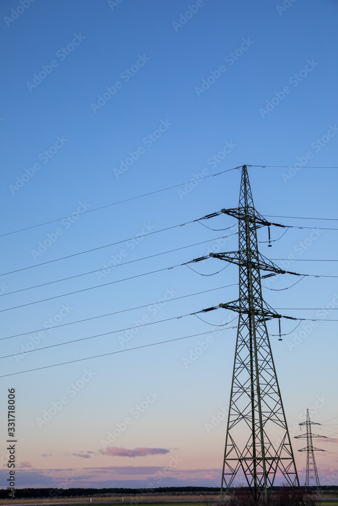 High voltage power lines with electricity pylons at twilight.