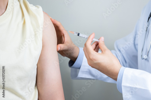 Asian man get coronavirus, flu and measles vaccine shot, vaccination in hospital for good heath, medicine injection vial dose for treatment patient. (select focus)