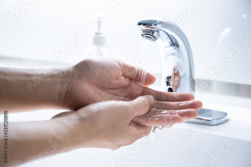 Man washing hands 7 step with soap or sanitizer gel on sinks faucet with water for clean virus and bacteria, health care concept (select focus)
