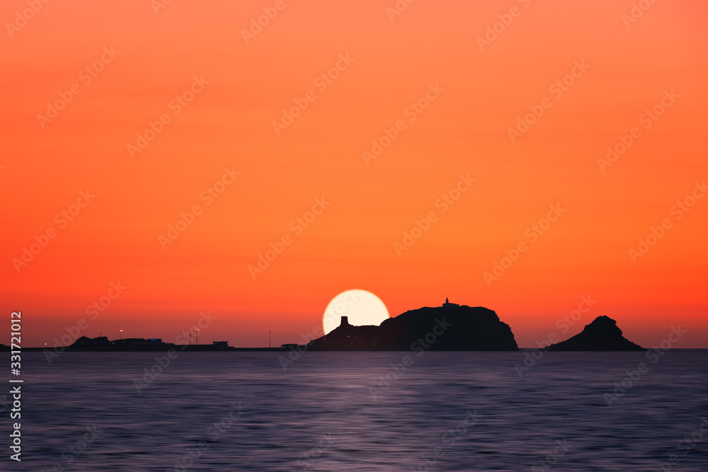 Sun setting behind La Pietra at Ile Rousse in Corsica