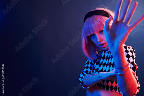 Portrait of young girl with blond hair in red and blue neon in studio