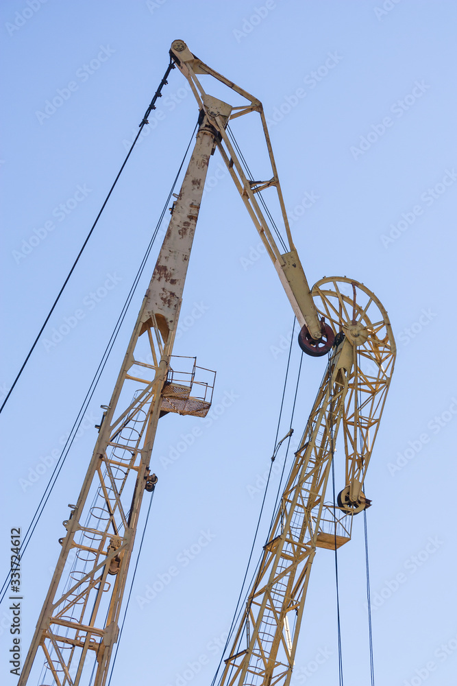 Large port cranes against a blue sky. Close-up of the construction elements of the crane. Large port cranes against a blue sky. Close-up of the construction elements of the crane.