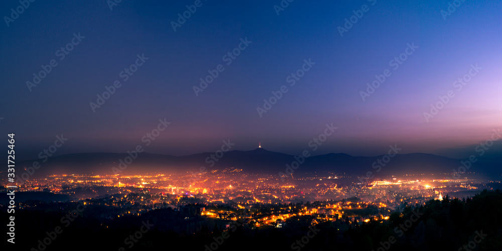 Shining town during dusk in the valley. Light fog flows above the town and disperse lights. Shining town during dusk in the valley. Light fog flows above the town and disperse lights.