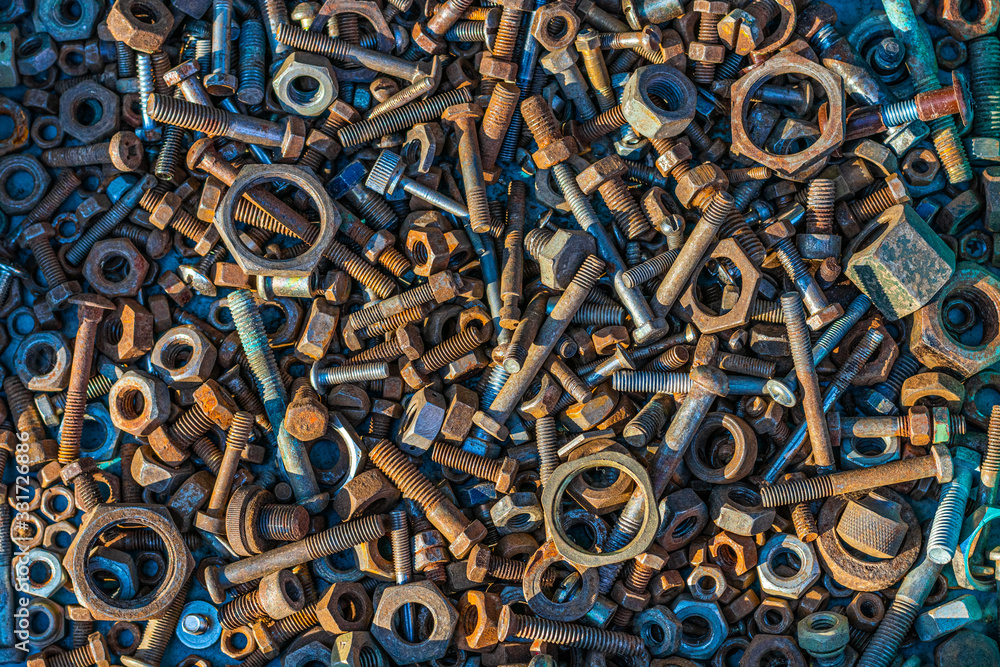 Many old rusty bolts and nuts of various sizes lie on the surface. Orange turquoise. Background or wallpaper.