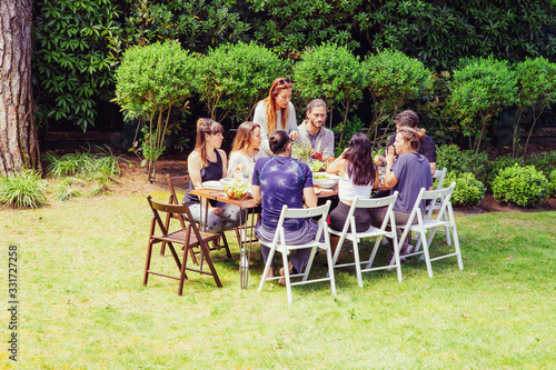Friends in sportswear eating outdoors. Sporty young male and female friends gathering around table and eating healthy dishes in backyard. Healthy lifestyle concept