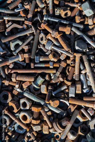 Many old rusty bolts and nuts of various sizes lie on the surface. Orange gray. Background or wallpaper.