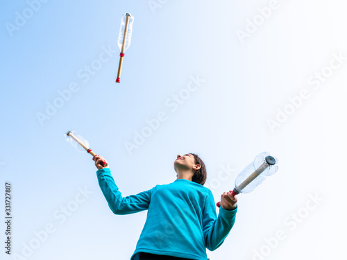 Billede på lærred teenage girl juggling with juggling clubs in the garden