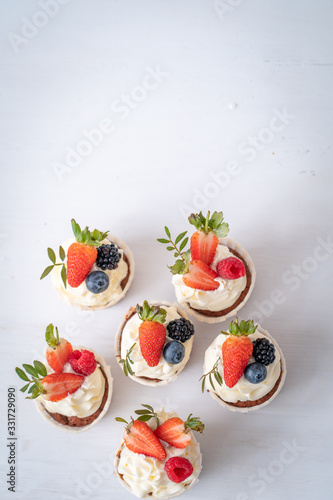 Fresh, delicious cupcakes with yogurt cream and fresh berries. Blur background.
