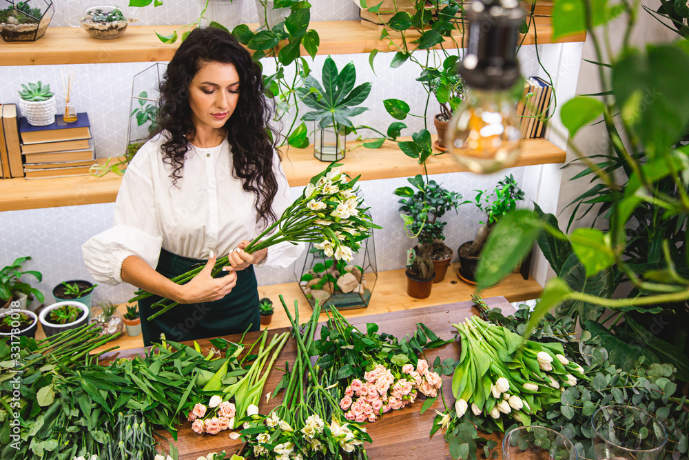 Attractive young woman florist is working in a flower shop. Attractive young woman florist is working in a flower shop.