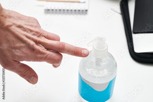 Close up of man giving middle finger to corona virus with hand disinfection gel bottle