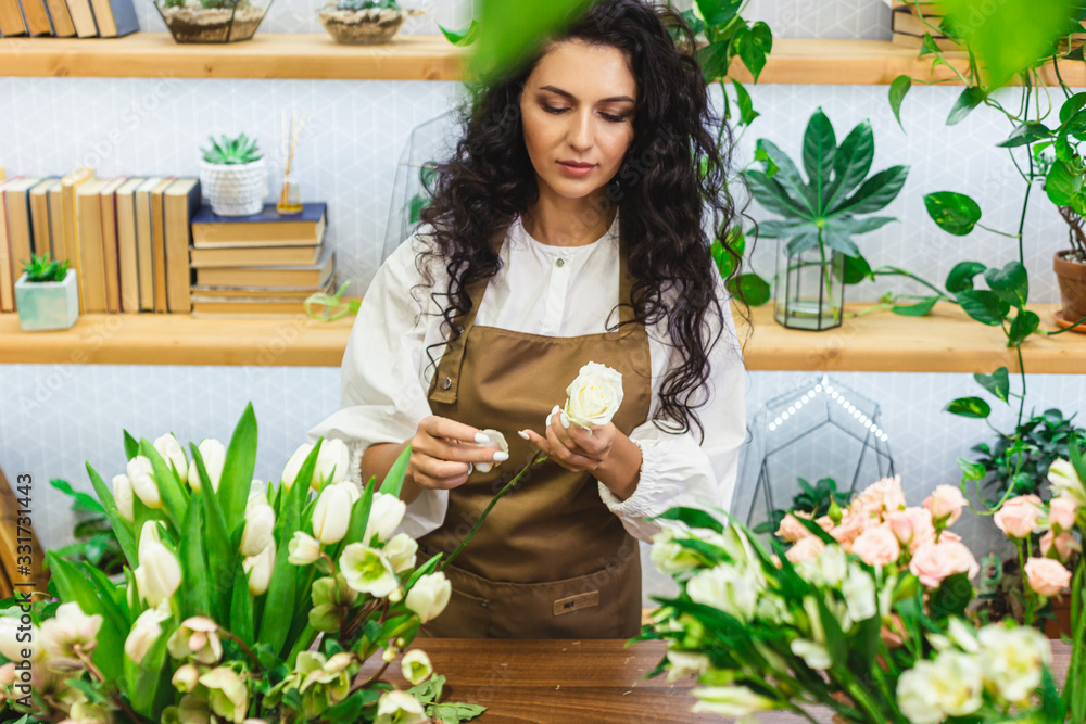 Obraz premium Attractive young woman florist is working in a flower shop.