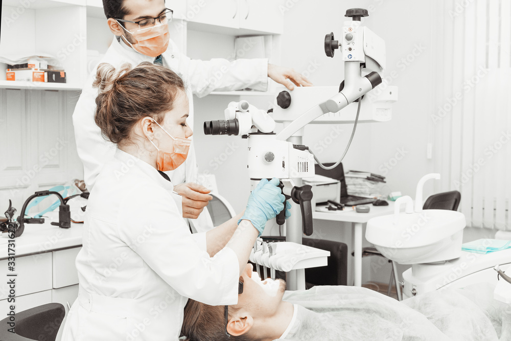 Obraz premium Two dentists treat a patient. Professional uniform and equipment of a dentist. Healthcare Equipping a doctor’s workplace. Dentistry