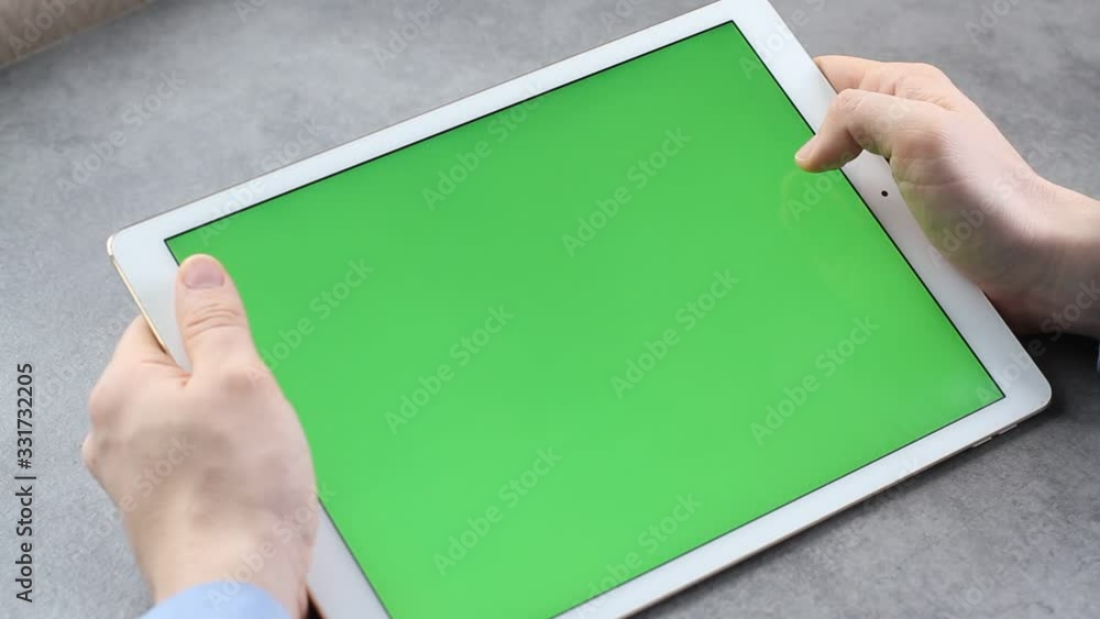 Man touches and looks at the screen of the tablet with a green screen. Chroma key on the screen of the tablet in businessman's hands Man touches and looks at the screen of the tablet with a green screen. Chroma key on the screen of the tablet in businessman's hands