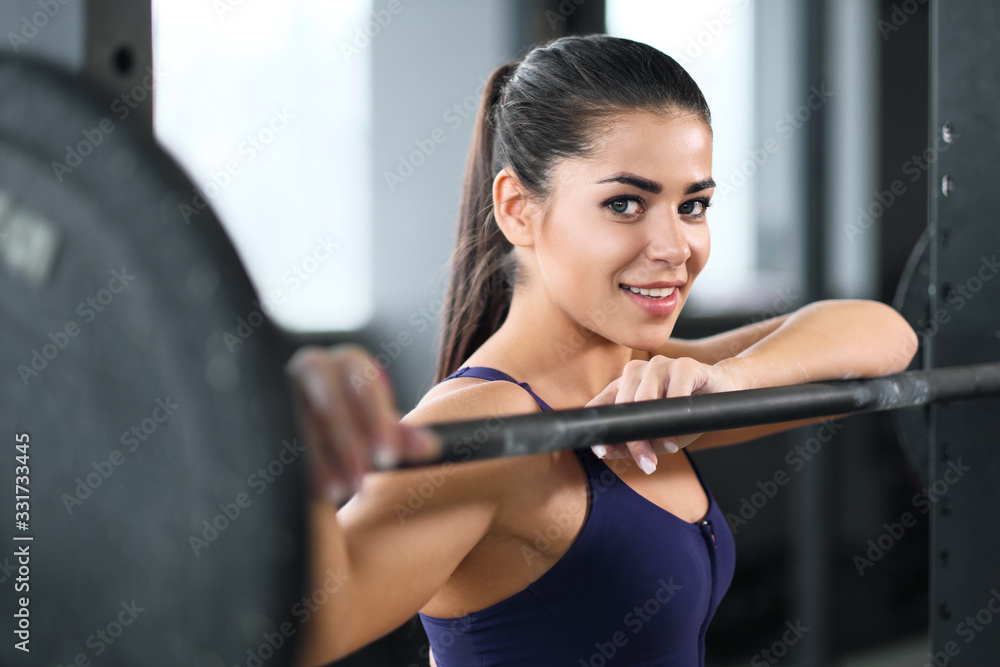 A beautiful athletic young brunette woman in sportswear in the gym performs exercises with a barbell. A beautiful athletic young brunette woman in sportswear in the gym performs exercises with a barbell.