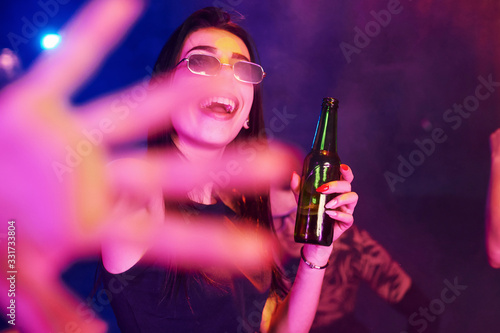 Defocused hand. Young people is having fun in night club with colorful laser lights