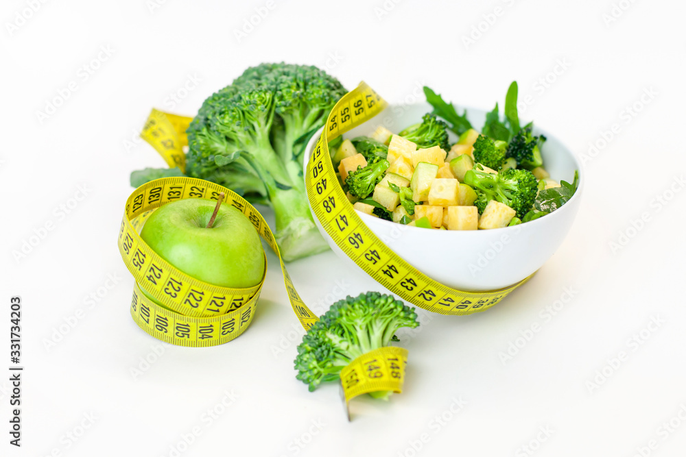 Vitamin-fitness diet, a plate of green salad, a green apple with a centimeter tape. Fresh Food and Roulette, Sports Diet, Raw Food Diet, Ketone Diet