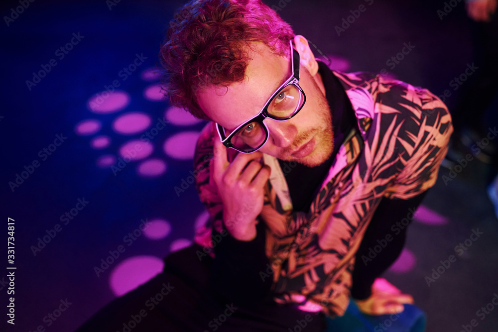 Young man in glasses have fun inside of night club with pink lightings Young man in glasses have fun inside of night club with pink lightings