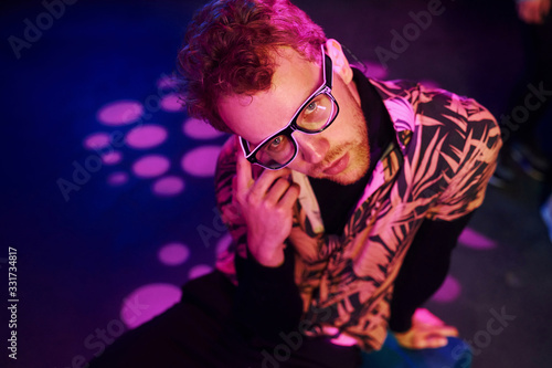 Young man in glasses have fun inside of night club with pink lightings