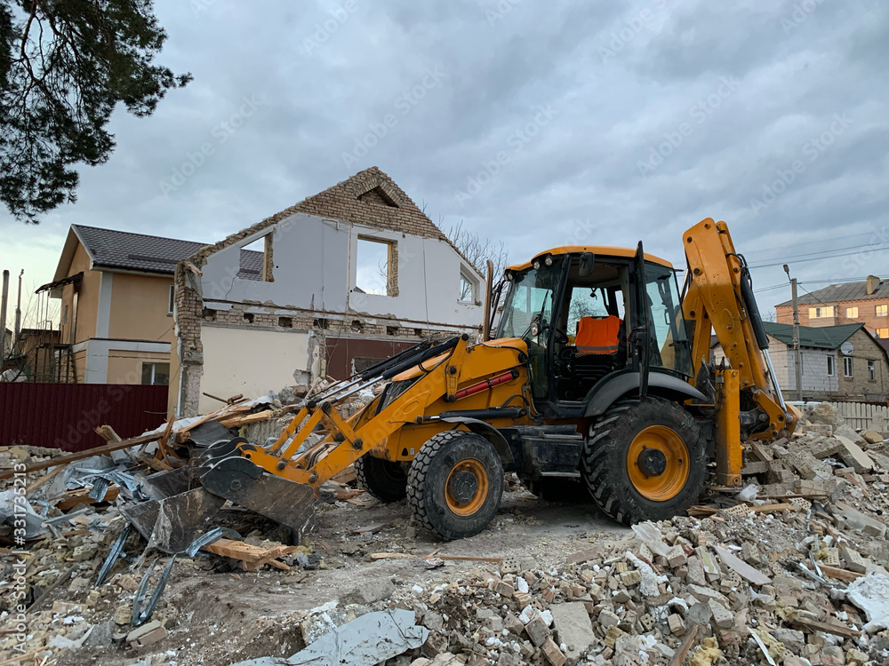 Ruined, brick, residential building. The ruins of a collapsed mansion in the forest. Demolition of an old house with an excavator. The destroyed walls of the building.