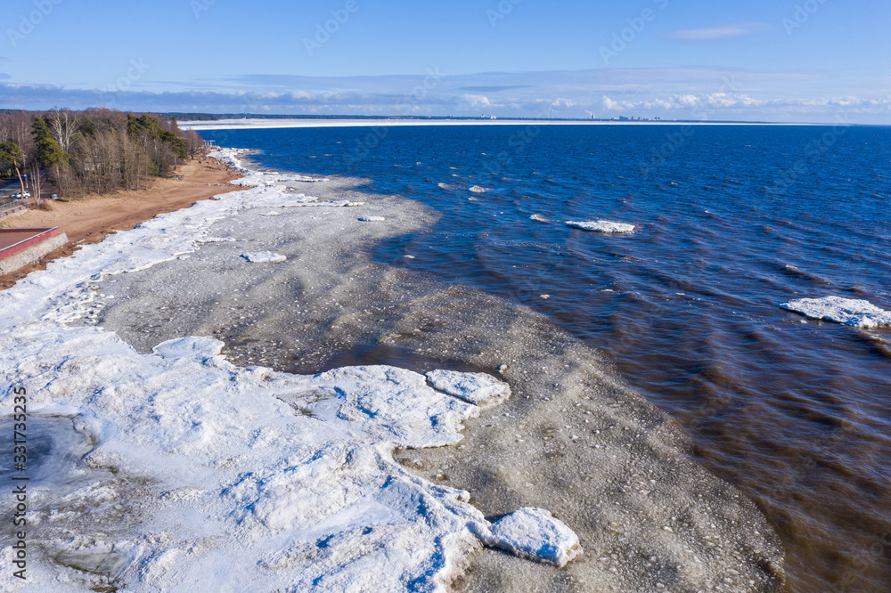 Fototapeta premium Aerial view of the coastline with pieces of ice floating on the waves