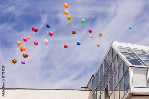 Light balloons released by children float in the air on a holiday. Beautiful balloons are flying against the background of a cloudy bright blue sky. photo