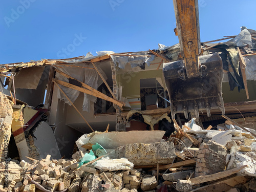 Heavy equipment near the destroyed brick house. Construction machinery on the background of the ruins of the house. Demolition of an old house with an excavator. Irpin, Kiev region, March 13.2020