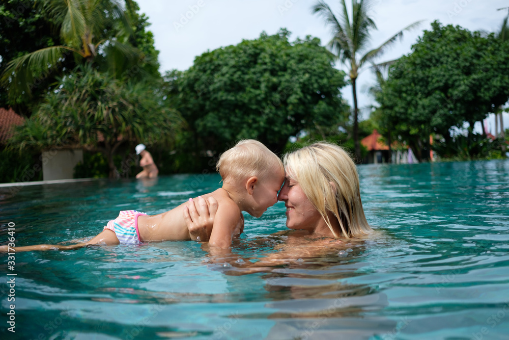 baby with mom learns to swim in the pool