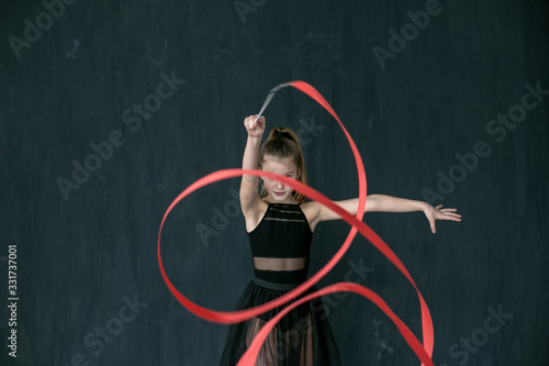horizontal portrait of a pretty gymnast performing an exercise with a red ribbon