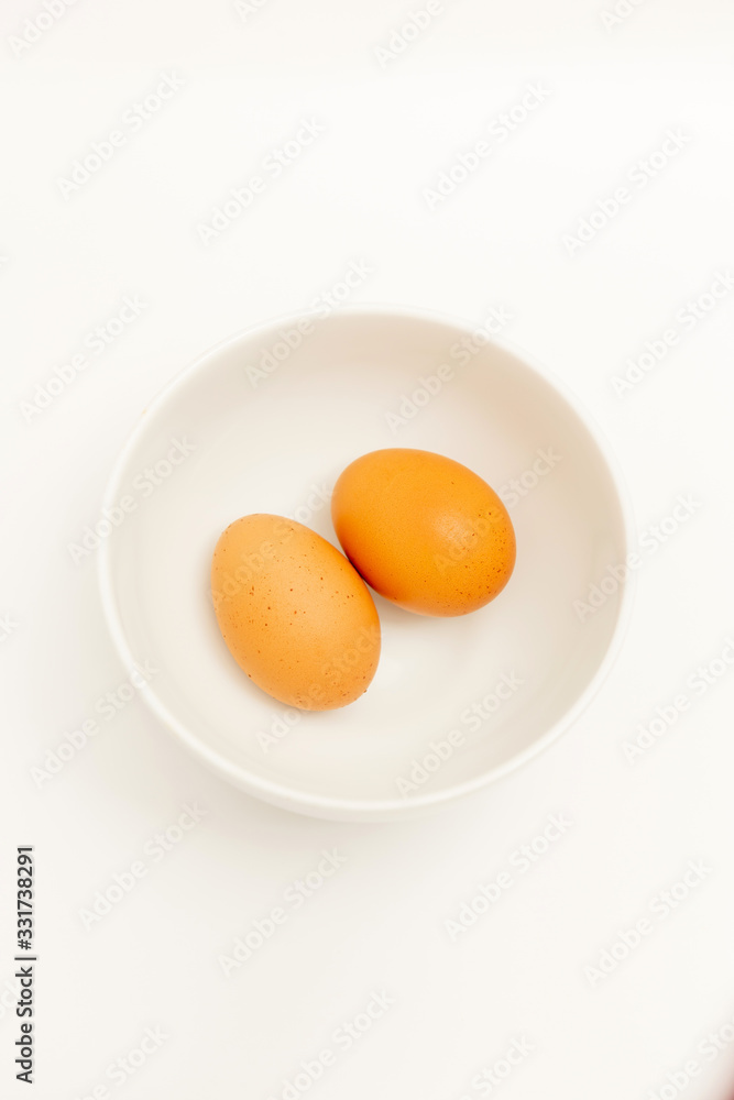 Two brown eggs isolated In a white cup on Wood background Two brown eggs isolated In a white cup on Wood background