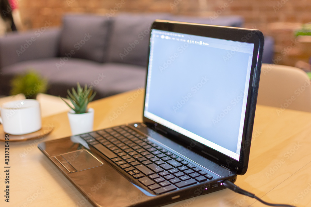 Laptop computer with blank screen and a cup of coffee on table at home interior in the evening. Laptop computer with blank screen and a cup of coffee on table at home interior in the evening.