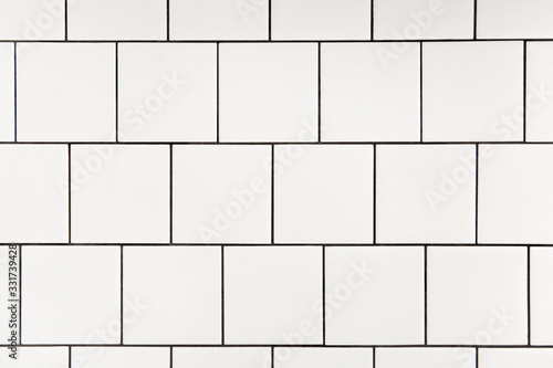 White square ceramic tile with black seam, located horizontally. Abstract background, ceramic texture. photo