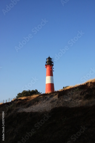 Red and white lighthouse on the island, blue sky background