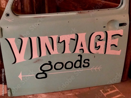 Directional sign pointing to vintage goods painted on an old car door