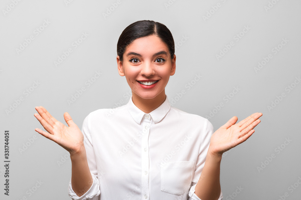the solution was found. young beautiful woman in white shirt with collar holding her palms up against grey background the solution was found. young beautiful woman in white shirt with collar holding her palms up against grey background