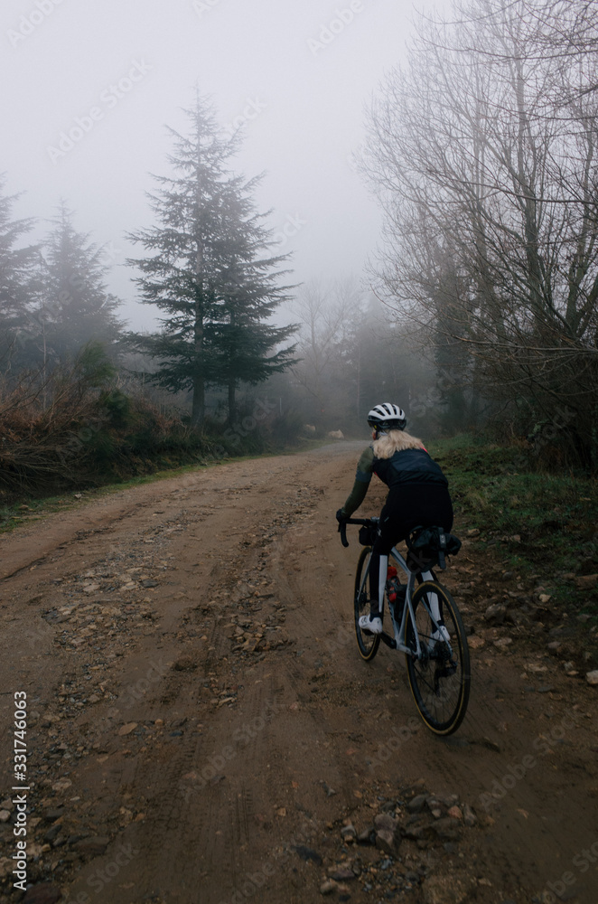 Female cyclist rides fast up a gravel road