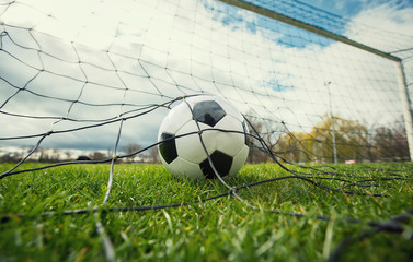 Close up of a soccer ball enters the gate and hits the net, goal concept. Football championship background, spring outdoors tournaments. Healthy sports activity and games.