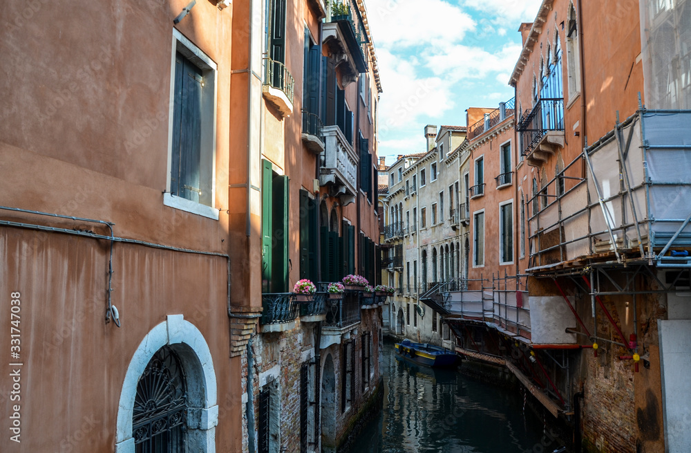 A typical alley of the old part of the island of Venice. The narrow channel between colorful historic houses. The romantic city, a place for tourists.